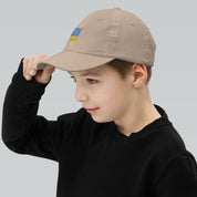 Young boy wearing a youth baseball cap with Ukrainian Tryzub emblem, showcasing its adjustable fit and breathable design.