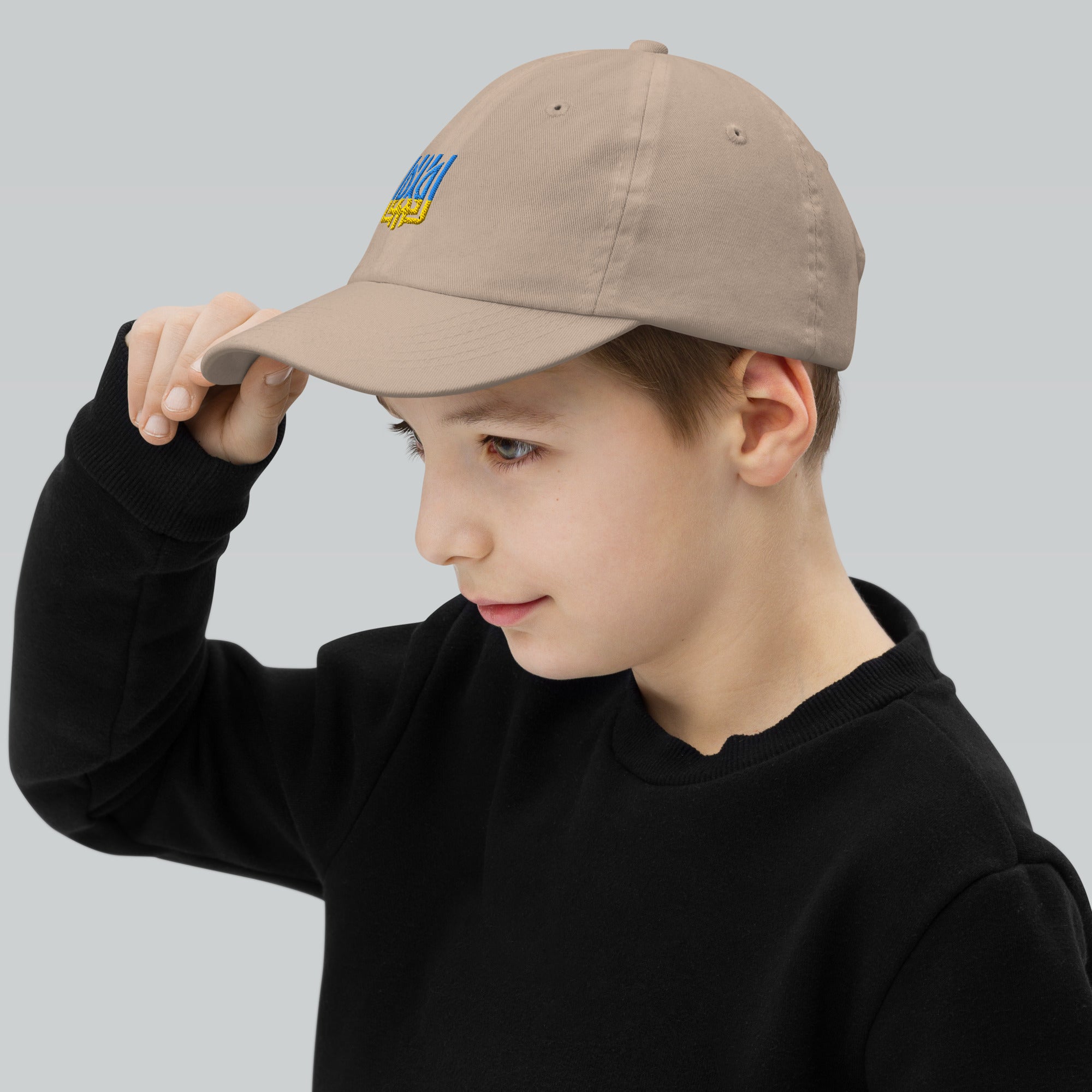 Young boy wearing a youth baseball cap with Ukrainian Tryzub emblem, showcasing its adjustable fit and breathable design.