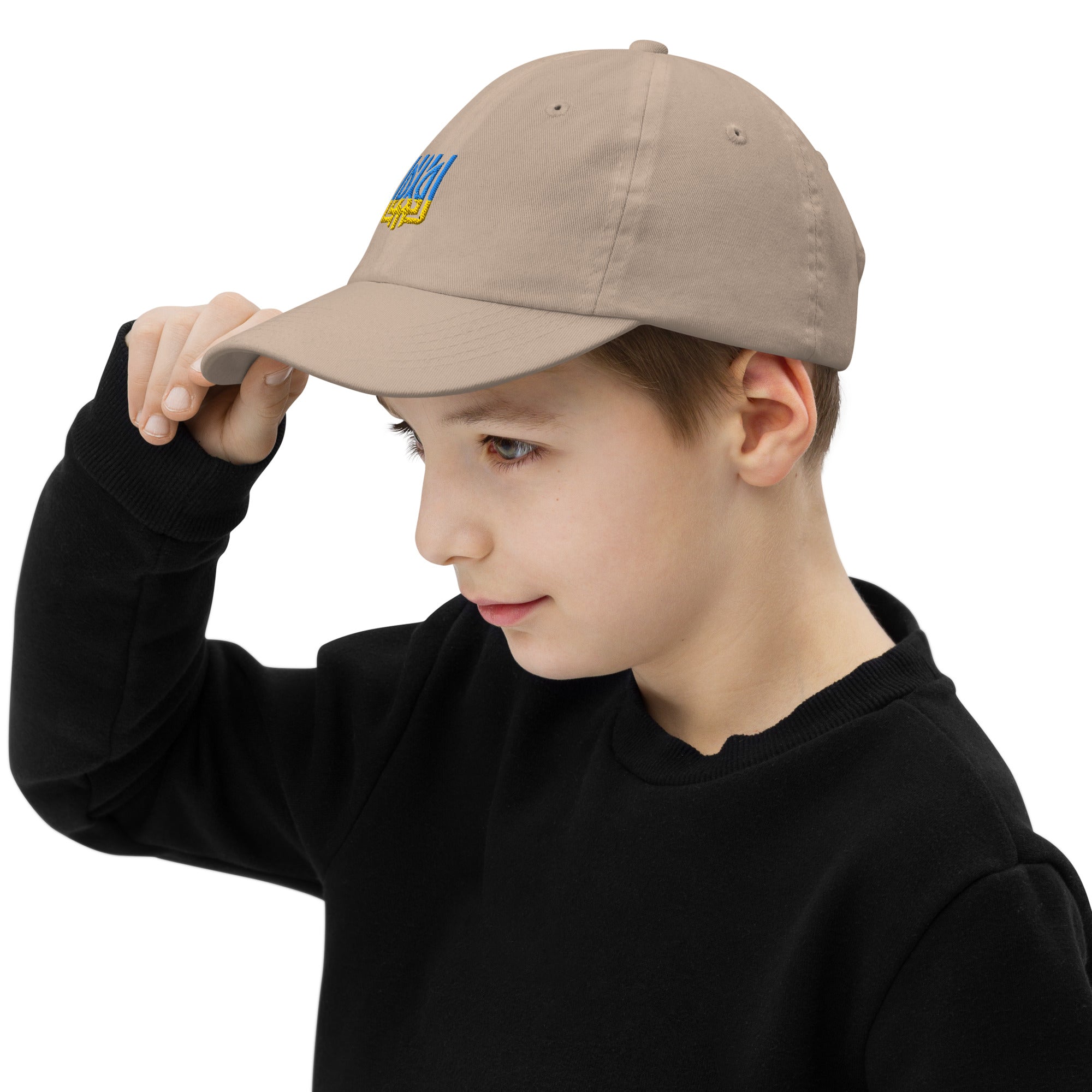 Child wearing a youth baseball cap with Ukrainian Tryzub emblem, adjusting the brim. Perfect for active kids, featuring breathable material.