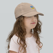 Girl wearing a youth baseball cap with Ukrainian Tryzub emblem, breathable and adjustable, ideal for sports or outdoor adventures.