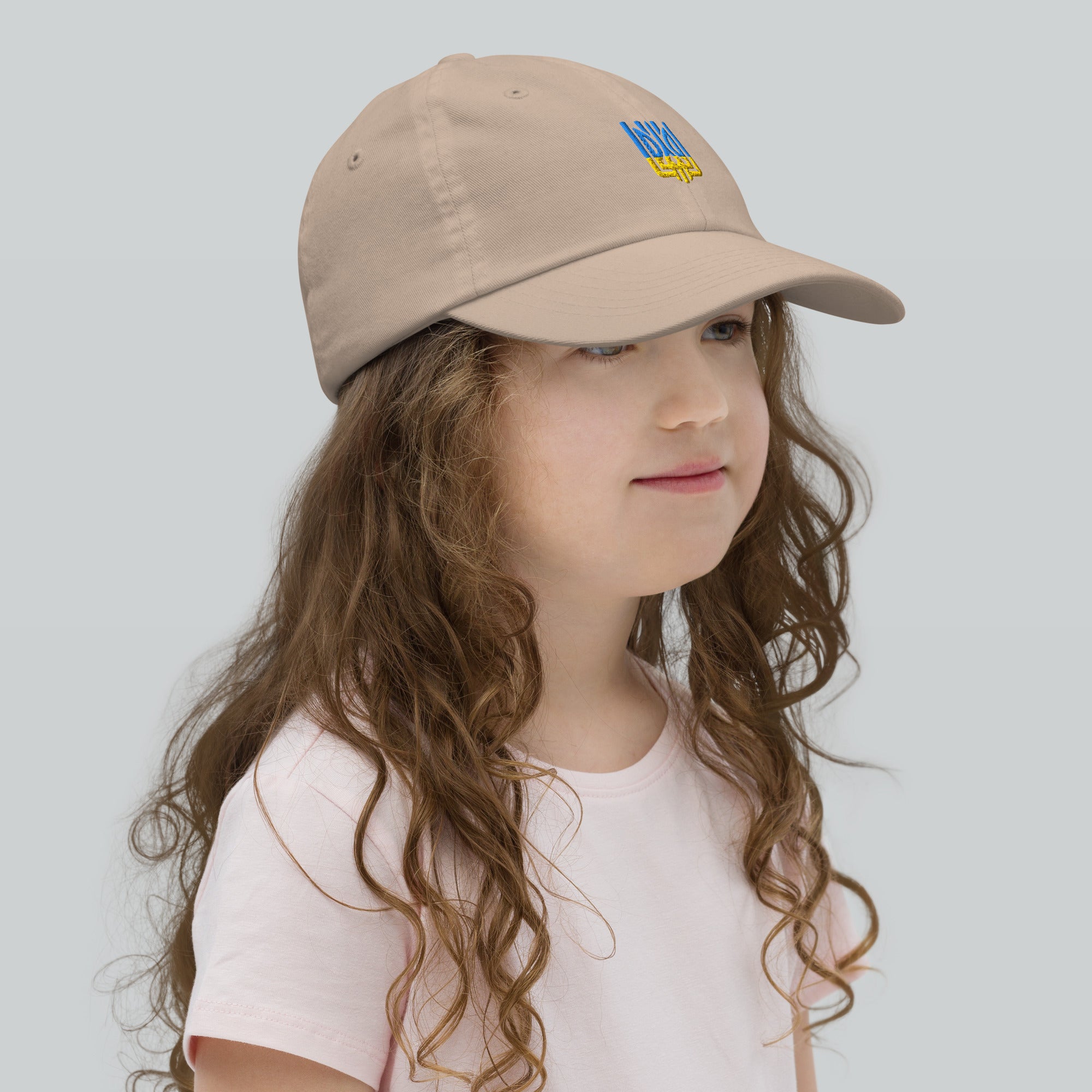 Girl wearing a youth baseball cap with Ukrainian Tryzub emblem, breathable and adjustable, ideal for sports or outdoor adventures.