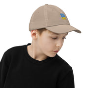 Child wearing a tan youth baseball cap with Ukrainian Tryzub emblem, breathable and adjustable for active kids.