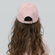 Back view of a child wearing a pink youth baseball cap, featuring an adjustable strap and ventilation eyelets, perfect for active outdoor play.