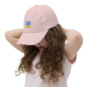 Child wearing a pink youth baseball cap with Ukrainian Tryzub emblem, featuring adjustable strap and breathable design for outdoor activities.