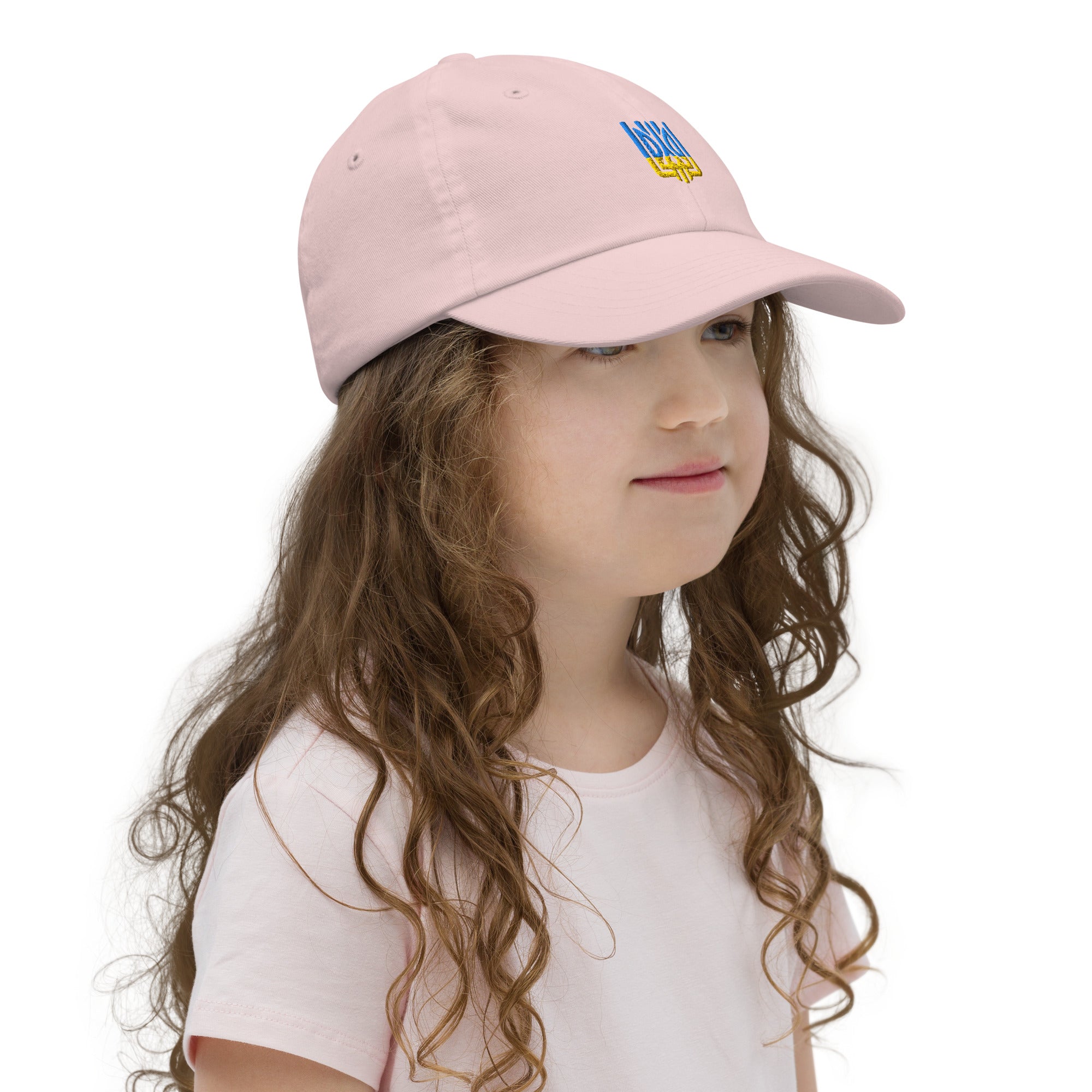 Young girl wearing a pink youth baseball cap with Ukrainian Tryzub emblem, made from bio-washed chino cotton, featuring an adjustable strap and ventilation.