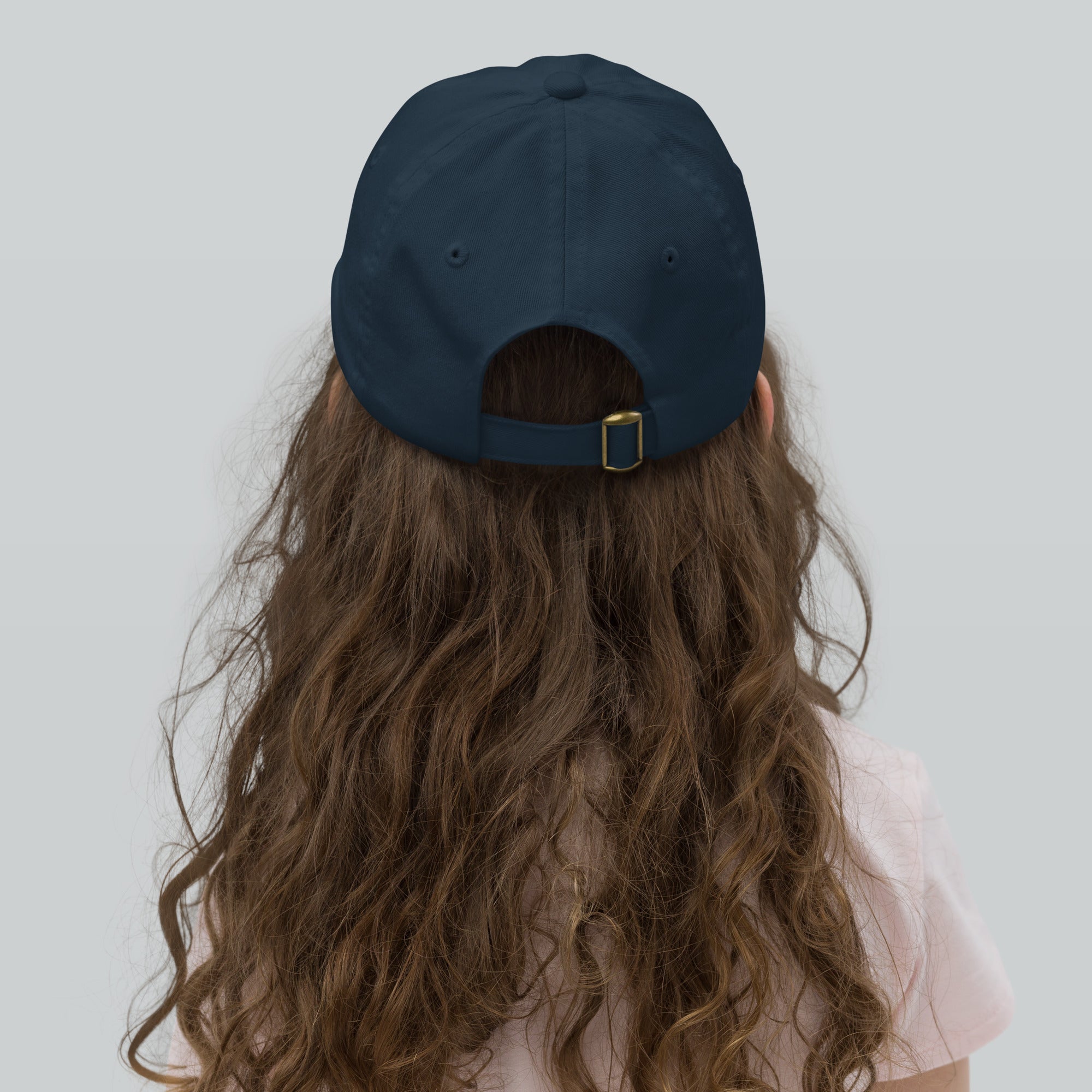 Child wearing adjustable youth baseball cap with Ukrainian Tryzub emblem, shown from the back, highlighting strap and bio-washed chino cotton.