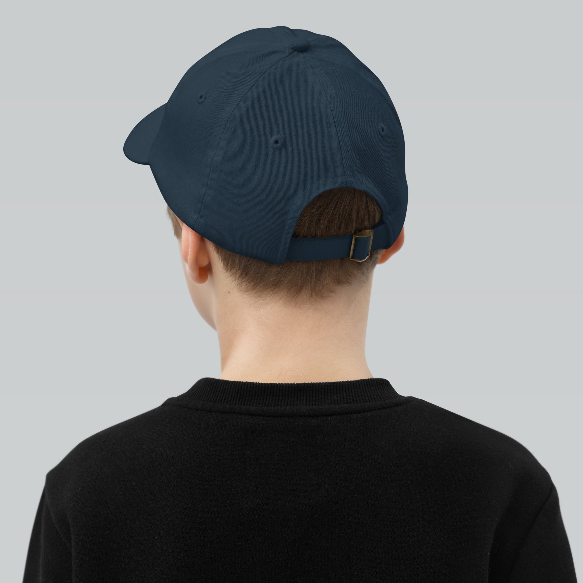 Child wearing youth baseball cap with adjustable strap and eyelets for ventilation, featuring Ukrainian Tryzub emblem.