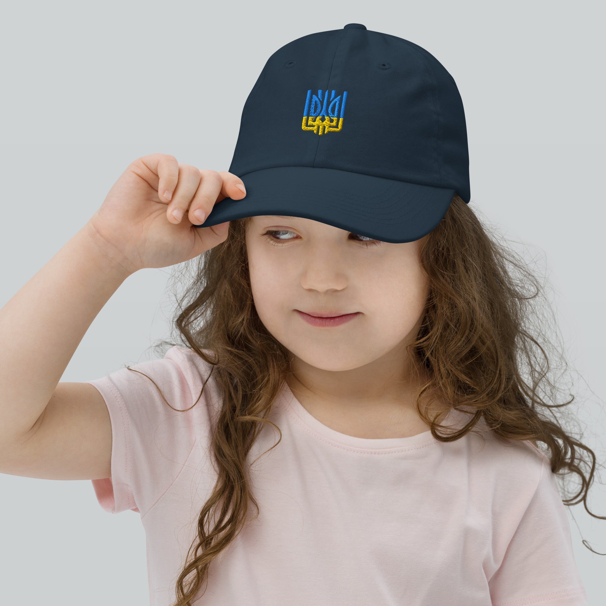 Child wearing a youth baseball cap with Ukrainian Tryzub emblem, breathable and adjustable for comfort and style, ideal for active kids.