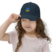 Young girl wearing a youth baseball cap with Ukrainian Tryzub emblem, showcasing a breathable and adjustable fit for active kids.