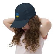Girl wearing youth baseball cap with Ukrainian Tryzub emblem, showing breathable and adjustable design for active kids.