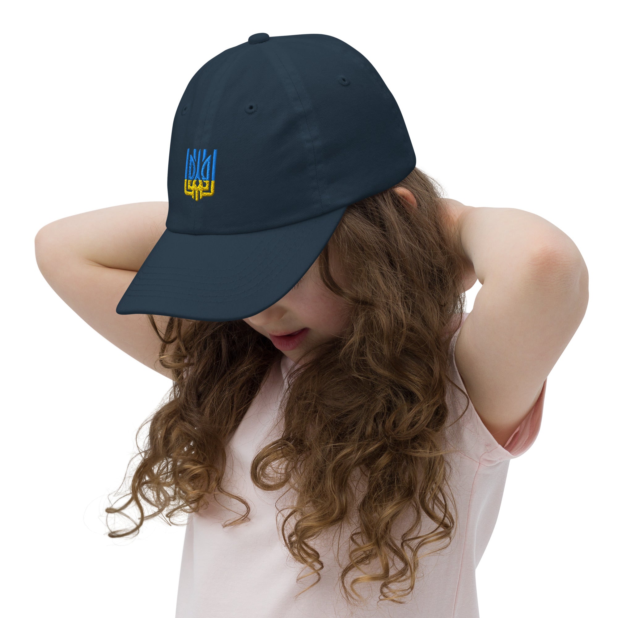 Girl wearing youth baseball cap with Ukrainian Tryzub emblem, showing breathable and adjustable design for active kids.