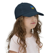 Young girl wearing a navy baseball cap with Ukrainian Tryzub for kids, breathable and adjustable for sports and outdoor activities.