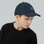 Child wearing a youth baseball cap with Ukrainian Tryzub emblem, perfect for active kids. Breathable and adjustable for comfort.
