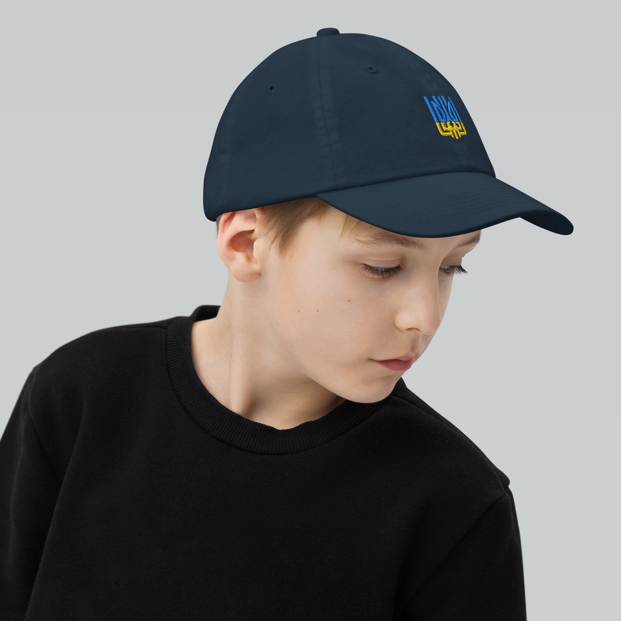 Child wearing a youth baseball cap with Ukrainian Tryzub emblem, perfect for active kids. Breathable and adjustable for comfort.