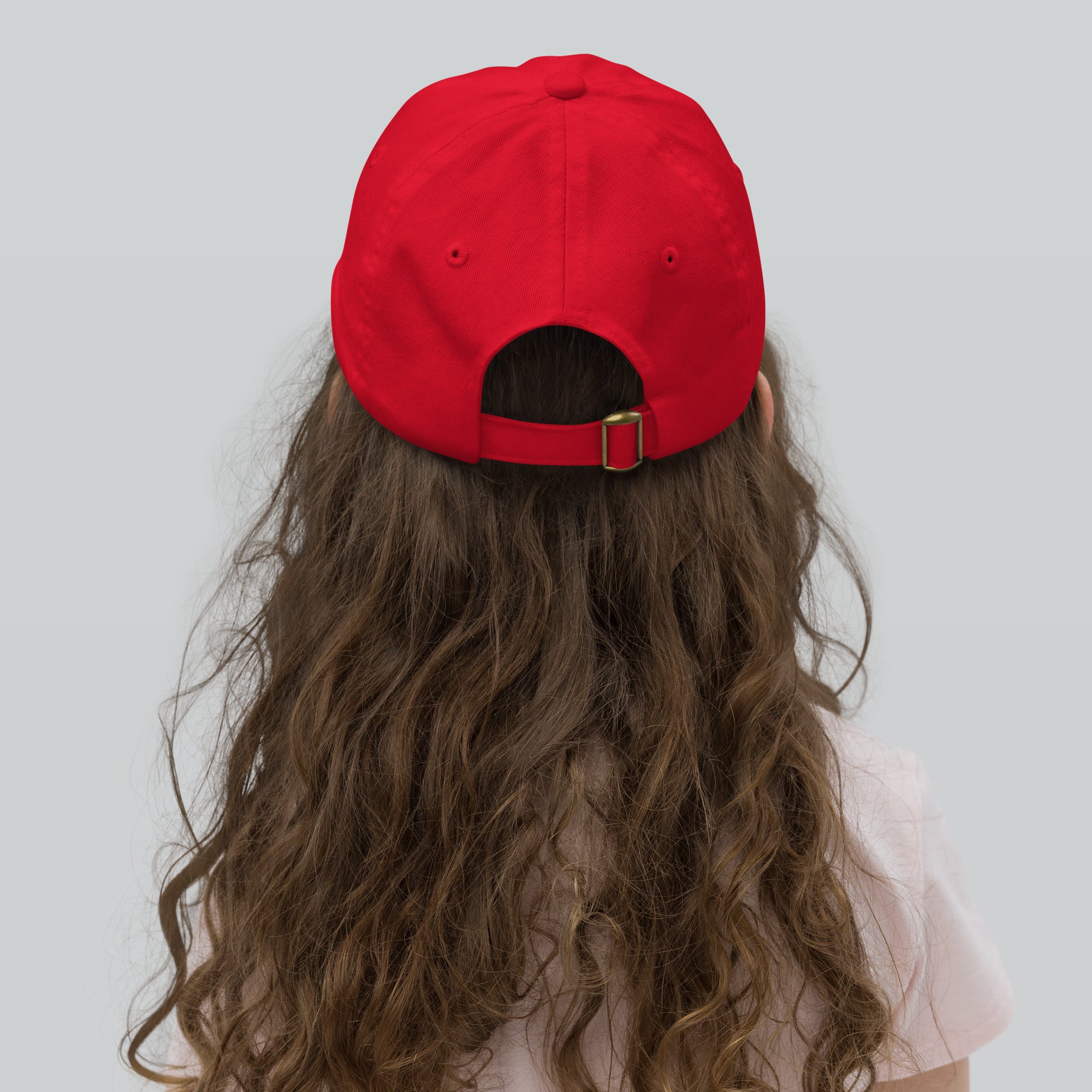 Youth wearing red baseball cap with adjustable strap, featuring Ukrainian Tryzub emblem, made of breathable biowashed cotton twill.