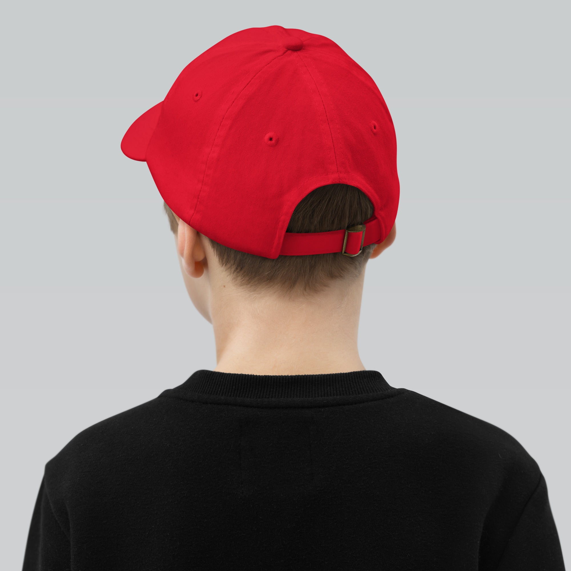 Rear view of a child wearing a red baseball cap, featuring an adjustable strap, ideal for active kids. Perfect for sports and outdoor adventures.