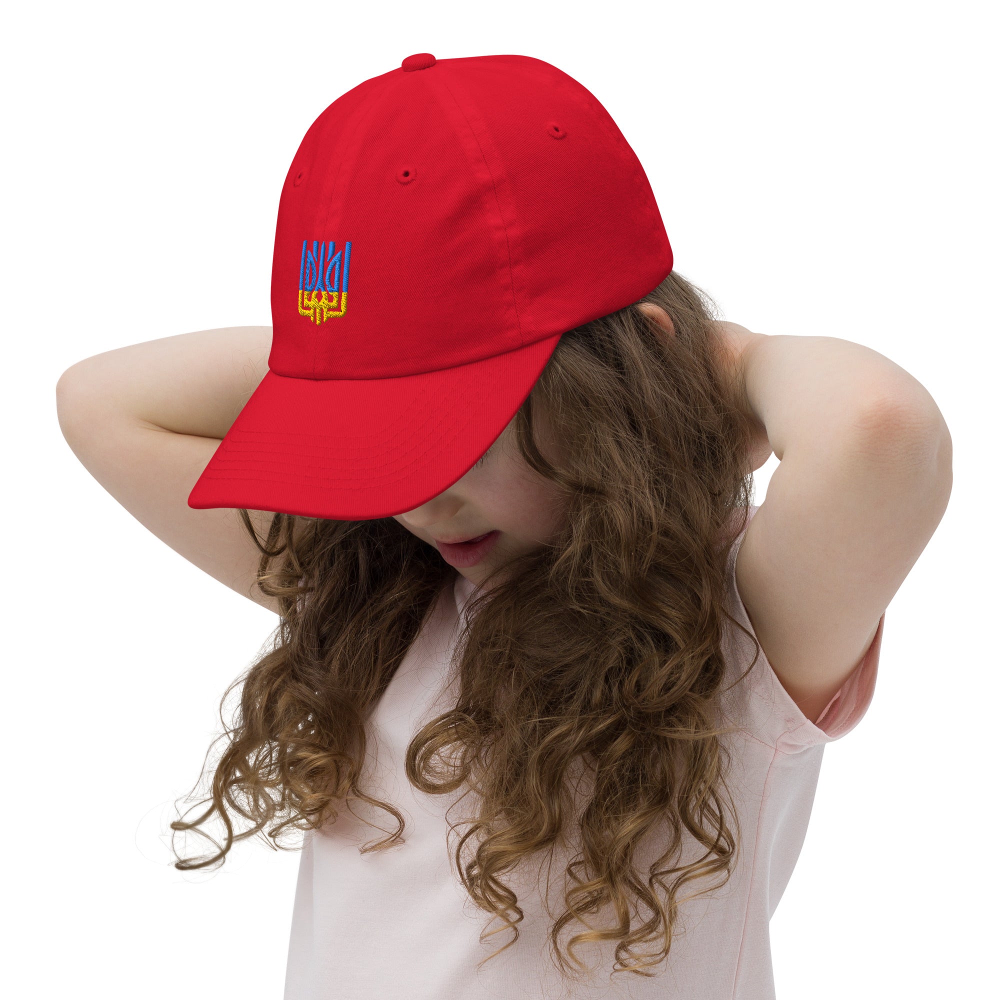 Child wearing a red youth baseball cap with Ukrainian Tryzub emblem, featuring breathable cotton and adjustable strap for active kids.