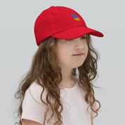Child wearing red youth baseball cap with Ukrainian Tryzub emblem, breathable and adjustable for active kids. Ideal for sports and outdoor play.
