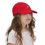 Girl wearing a red youth baseball cap with Ukrainian Tryzub emblem, breathable with adjustable strap, ideal for active kids.