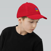 Youth wearing red baseball cap with Ukrainian Tryzub emblem, breathable and adjustable for active play