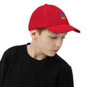 Child wearing red youth baseball cap with Ukrainian Tryzub emblem. Breathable, adjustable design ideal for active kids.