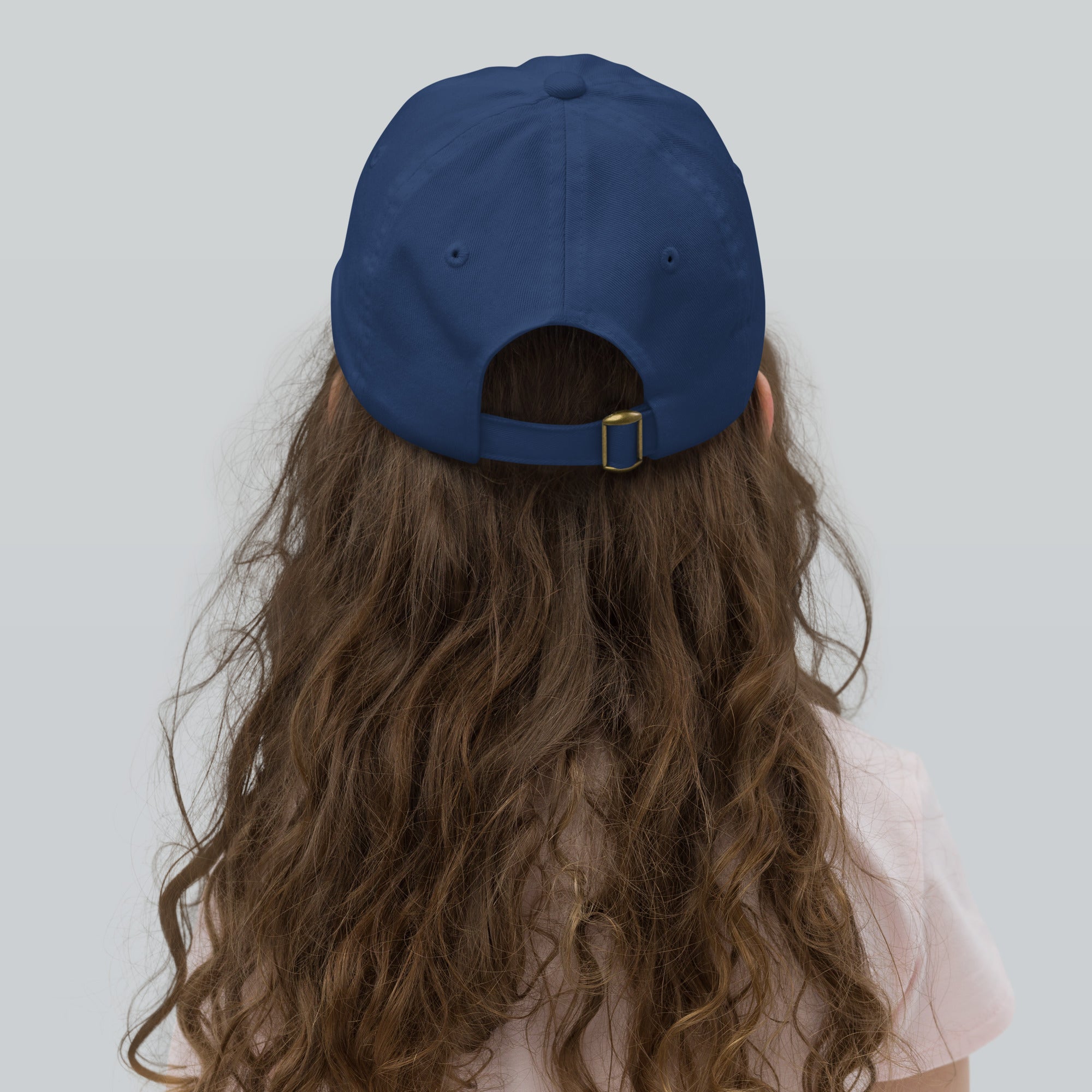 Child wearing blue youth baseball cap with adjustable strap and breathable design, ideal for sports and outdoor activities.