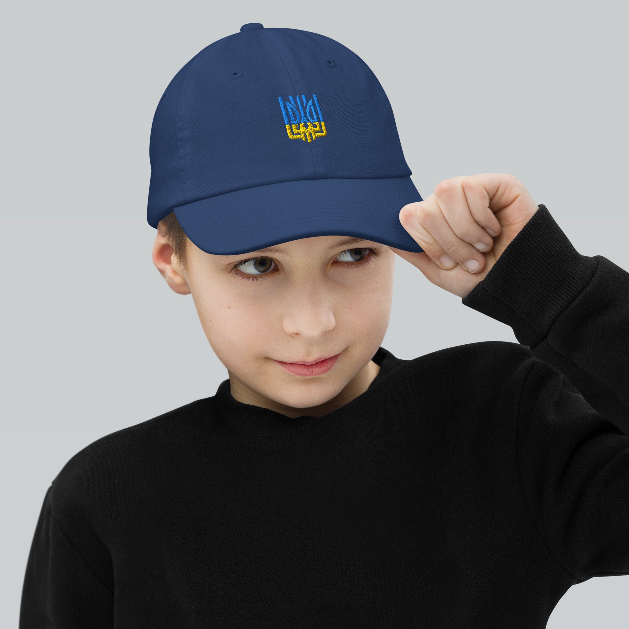 Child wearing a blue youth baseball cap with Ukrainian Tryzub emblem, showcasing adjustable fit and breathable fabric for active kids