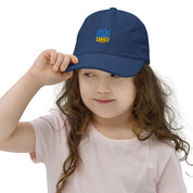 Girl wearing navy youth baseball cap with Ukrainian Tryzub emblem, ideal for sports and outdoor activities, with adjustable strap.