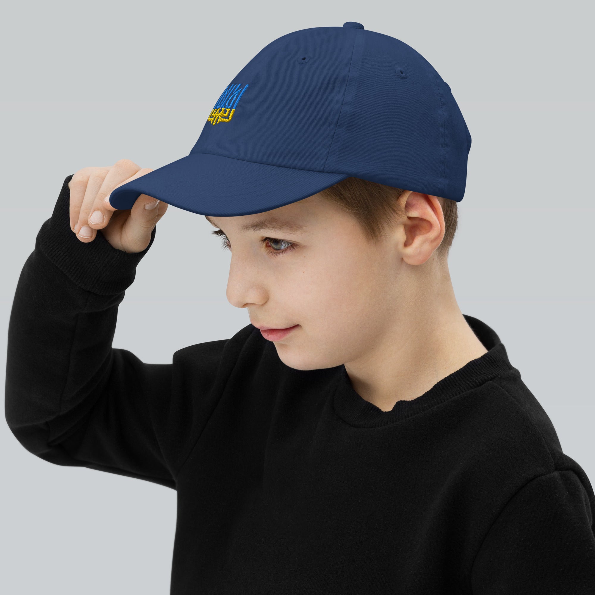 Child wearing blue youth baseball cap with Ukrainian Tryzub emblem, perfect for active kids. Made from breathable, adjustable cotton twill.