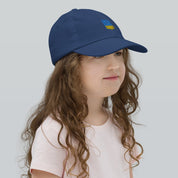 Child wearing blue baseball cap with Ukrainian Tryzub emblem, breathable and adjustable, ideal for active kids and outdoor activities.
