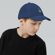 Boy wearing a blue youth baseball cap with Ukrainian Tryzub emblem, perfect for outdoor activities and everyday wear.