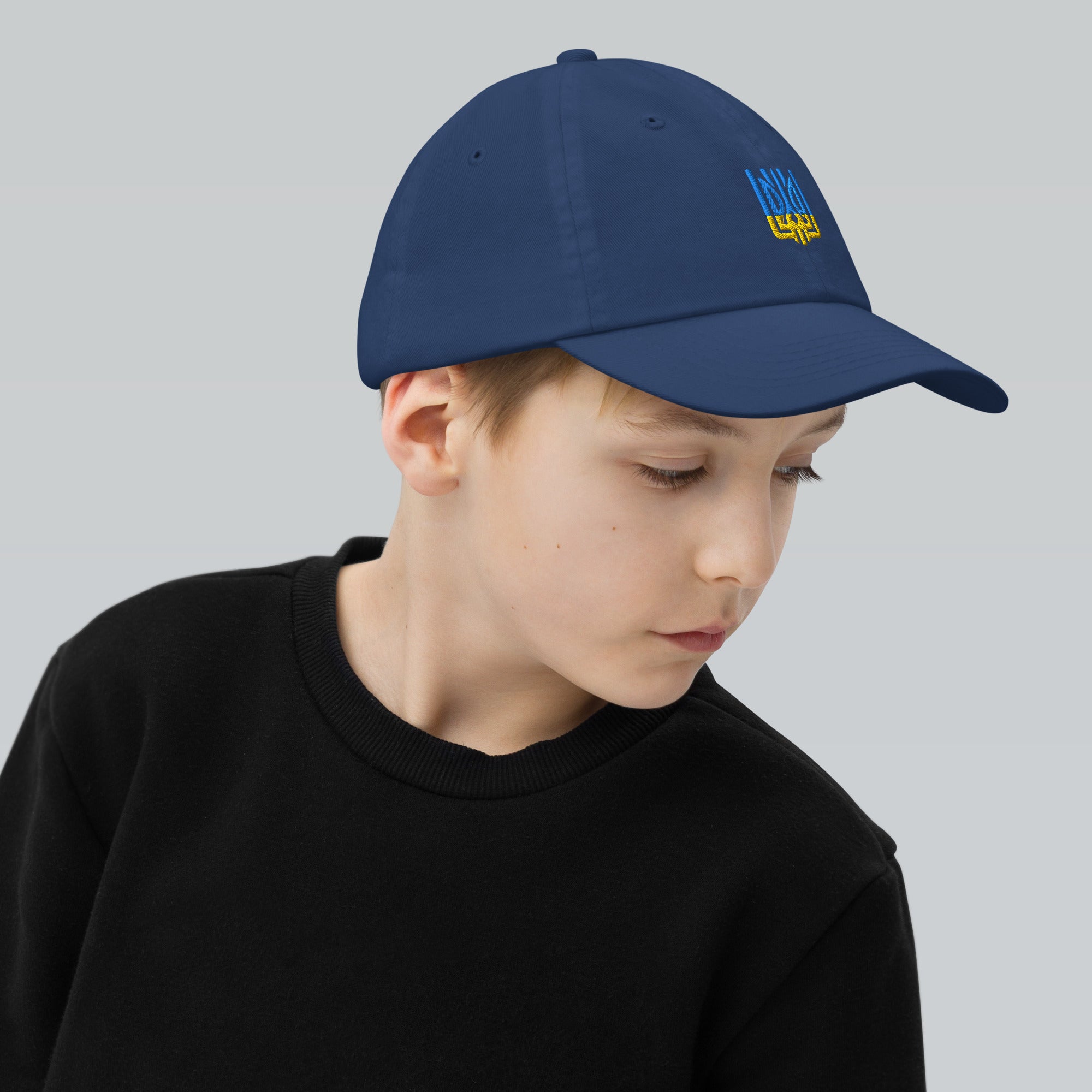 Boy wearing a blue youth baseball cap with Ukrainian Tryzub emblem, perfect for outdoor activities and everyday wear.