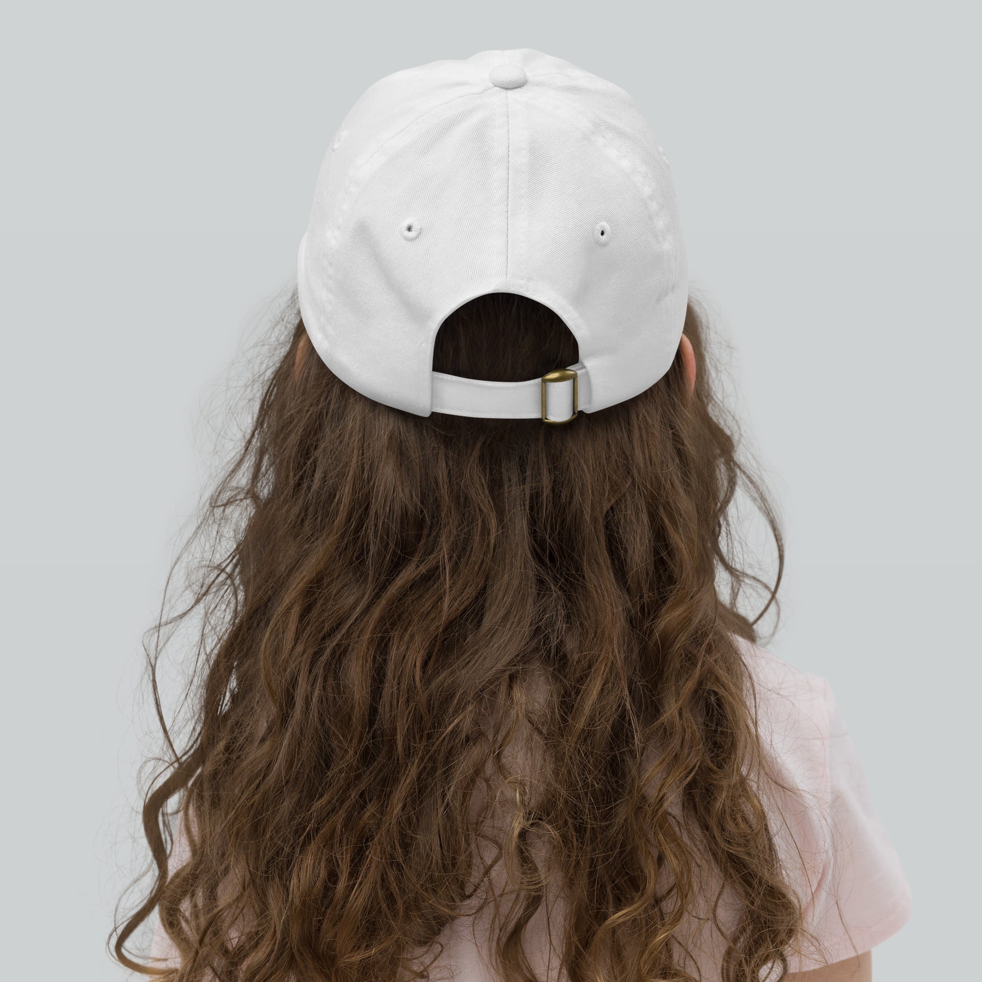 Rear view of a youth wearing a white baseball cap with an adjustable strap, ideal for outdoor play and sun protection.