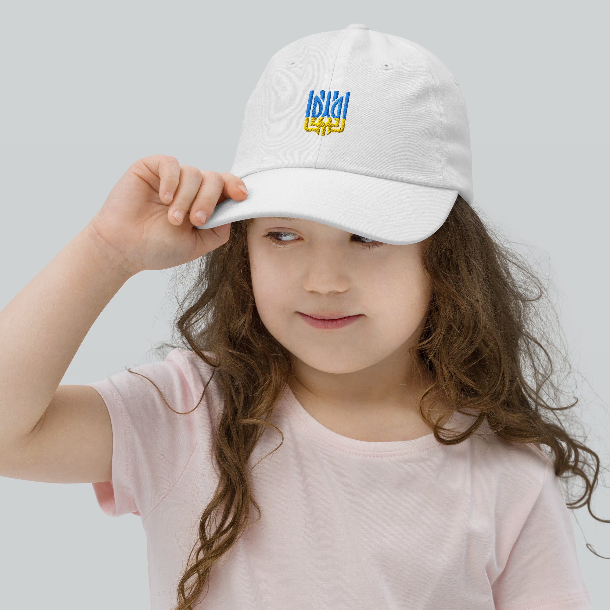 Girl wearing youth baseball cap with Ukrainian Tryzub, breathable and adjustable, ideal for outdoor activities.