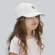 Young girl wearing a white youth baseball cap with Ukrainian Tryzub design, perfect for active kids and outdoor adventures.