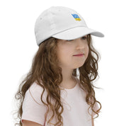 Girl wearing youth baseball cap with Ukrainian Tryzub emblem, breathable and adjustable for active kids.