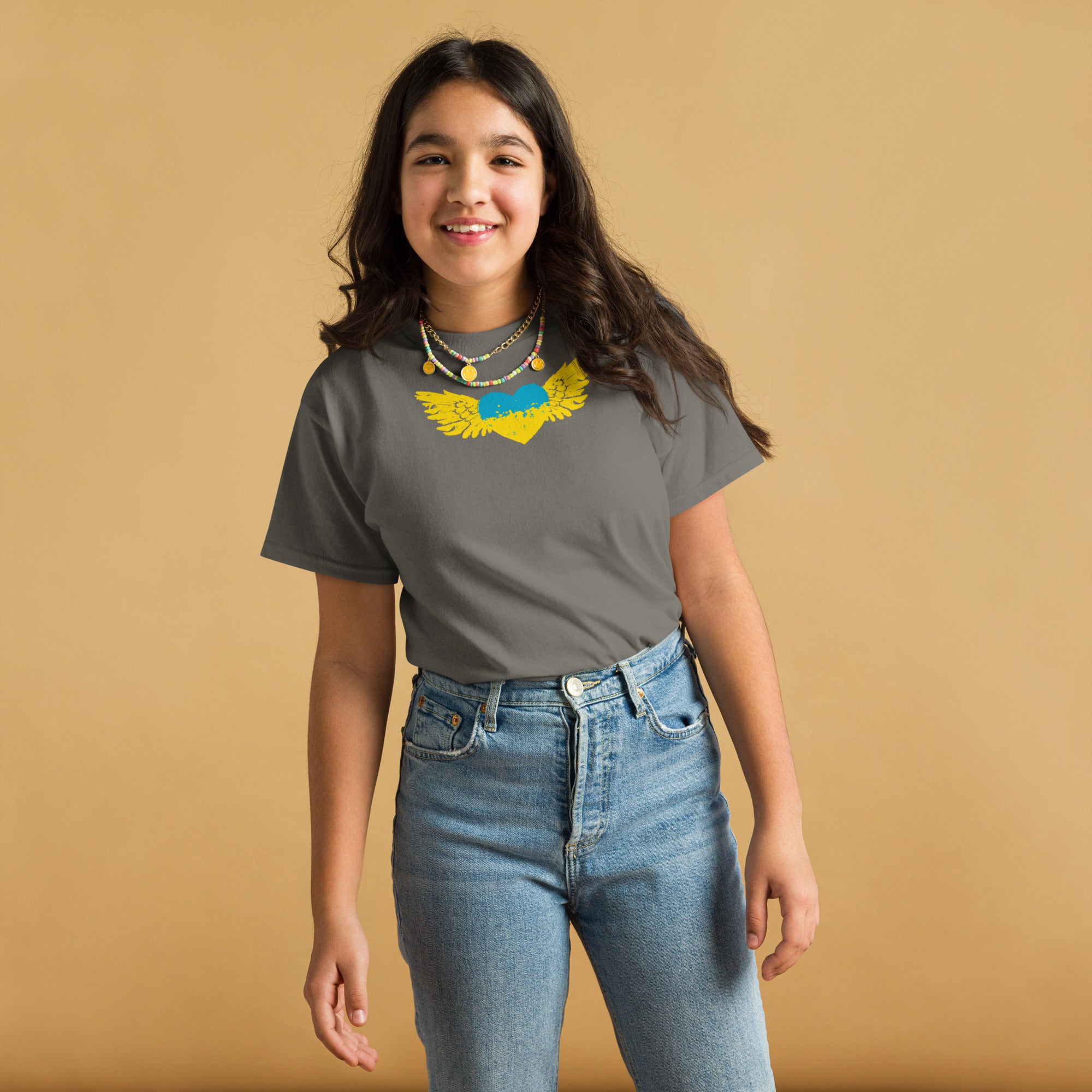 Girl wearing a youth classic t-shirt with Ukrainian Tryzub emblem, showcasing culture and pride, against a neutral background.