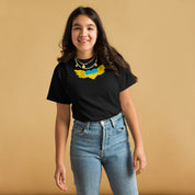 Girl wearing a Youth Classic T-Shirt with Ukrainian Tryzub emblem, standing, smiling, showcasing cultural pride and style.
