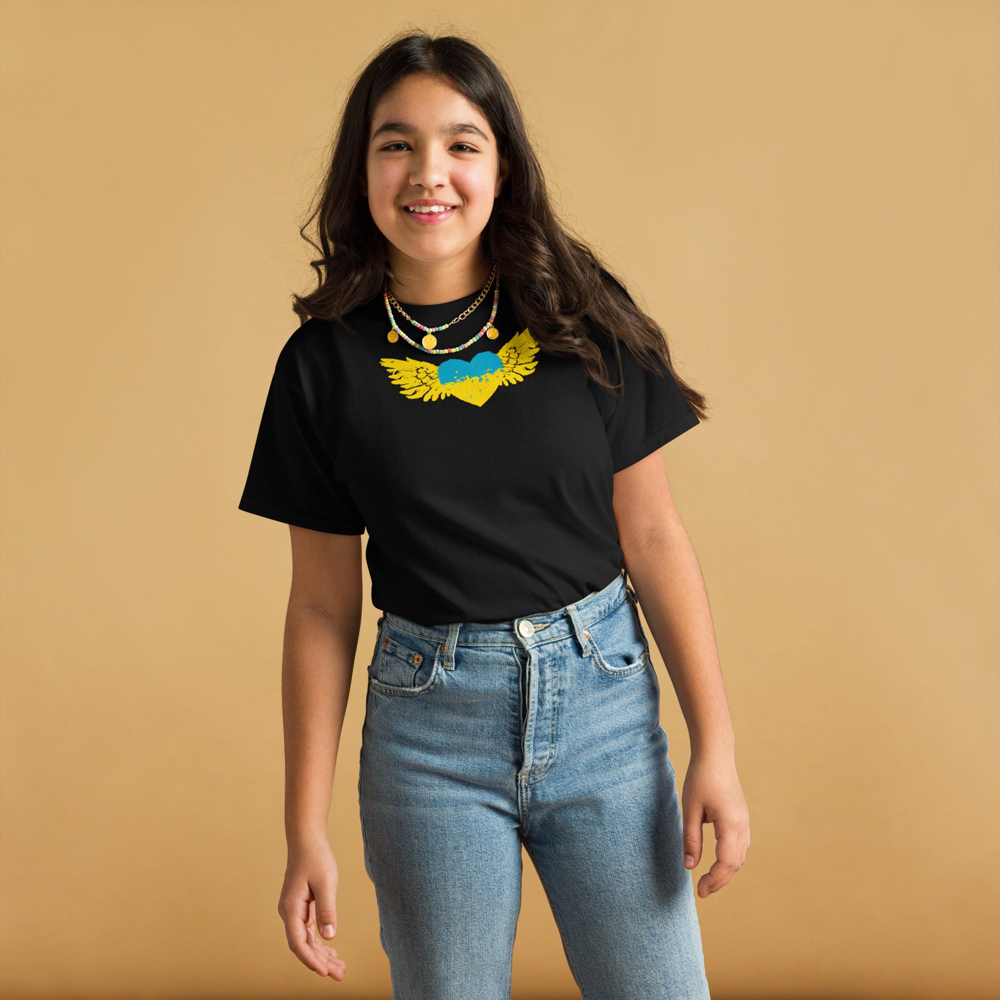 Girl wearing a Youth Classic T-Shirt with Ukrainian Tryzub emblem, standing, smiling, showcasing cultural pride and style.