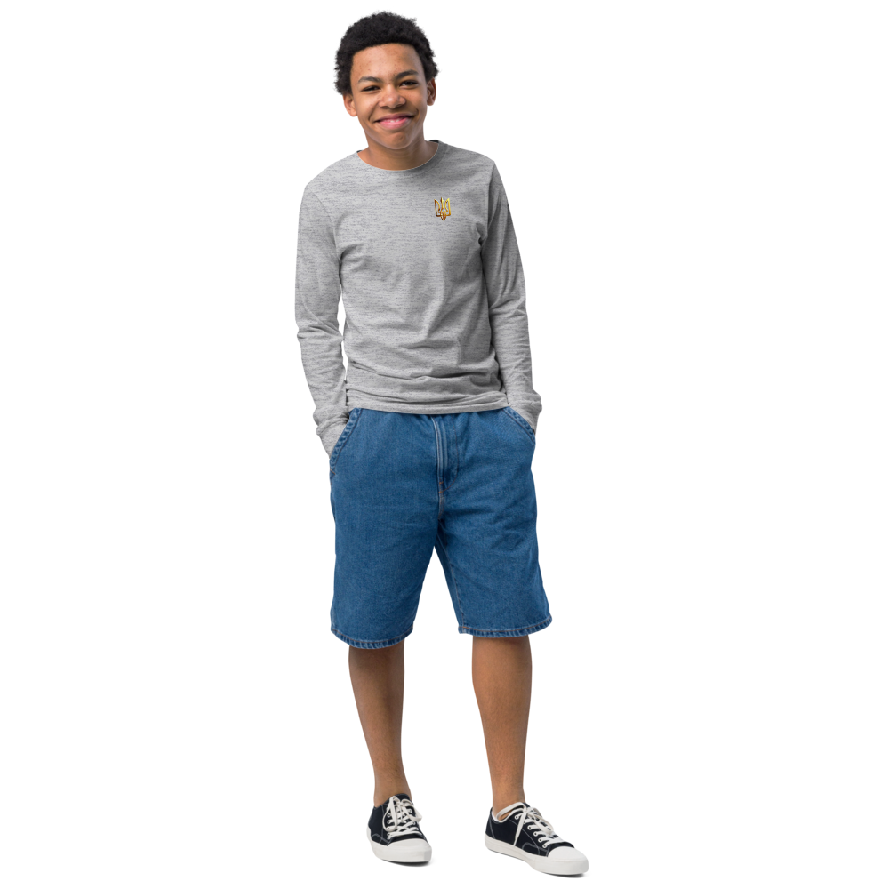 Youth long sleeve shirt with golden Ukrainian Trizub on heart, soft cotton, regular fit, classic crew neck, ribbed cuffs, modeled outdoors.