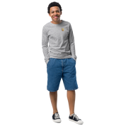 Youth long sleeve shirt with golden Ukrainian Trizub on heart, soft cotton, regular fit, classic crew neck, ribbed cuffs, modeled outdoors.