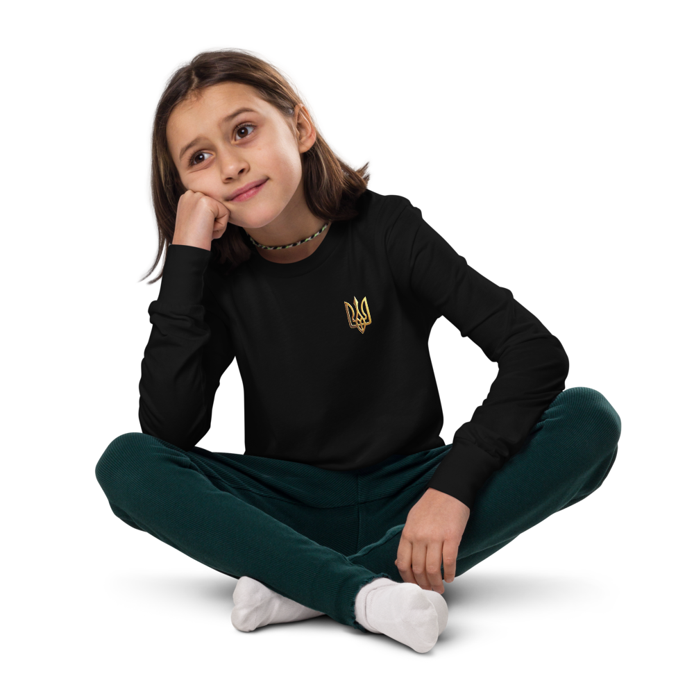 Youth wearing black long sleeve shirt with golden Ukrainian Trizub, sitting comfortably with legs crossed, showcasing cultural pride.