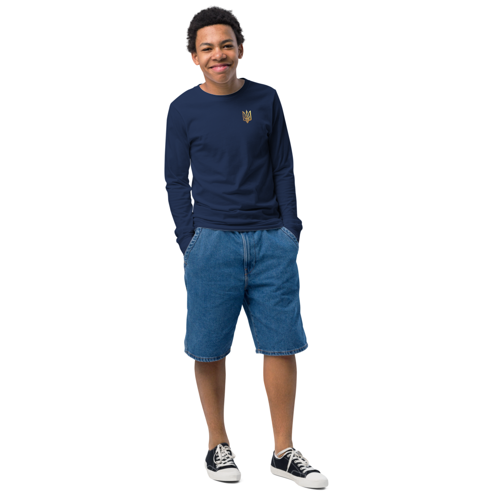 Youth wearing long sleeve shirt with golden Ukrainian Trizub on chest, styled with denim shorts and sneakers.