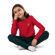 Youth long sleeve shirt with gold Ukrainian Trizub on heart, worn by a child.