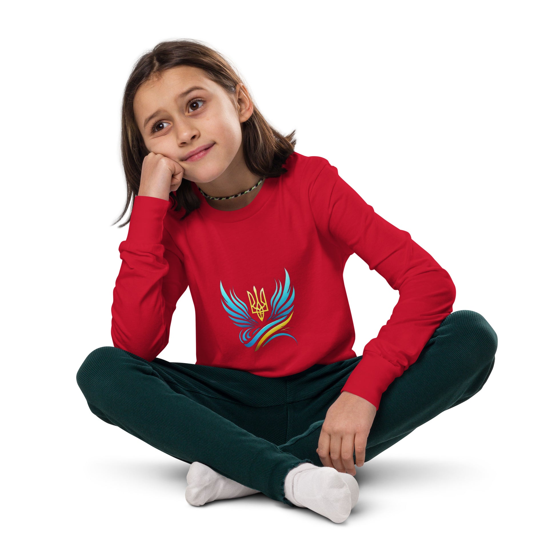 Youth wearing a red long sleeve tee with Ukrainian Vibe Tryzub logo, sitting cross-legged and looking thoughtful.