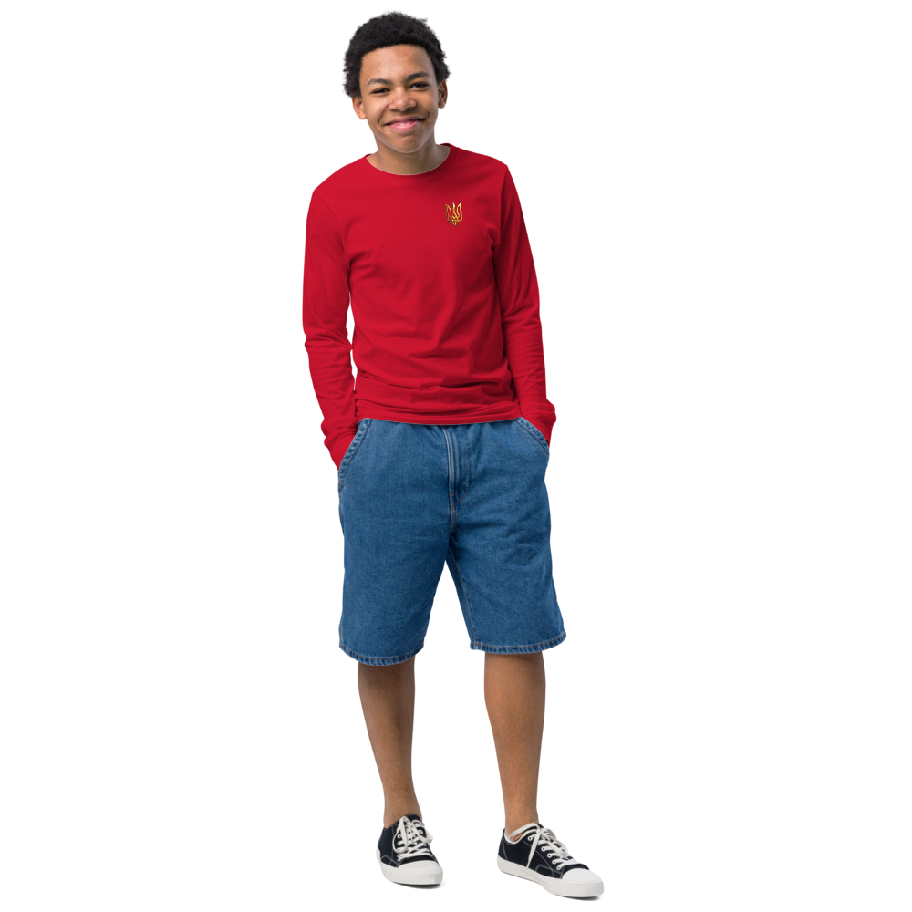 Youth wearing red long sleeve shirt featuring golden Ukrainian Trizub on heart, paired with denim shorts, showcasing cultural pride.