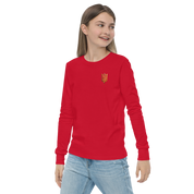 Youth wearing red long sleeve shirt with golden Ukrainian Trizub on heart, showcasing cultural pride and style.