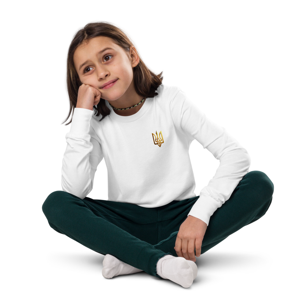 Youth wearing long sleeve shirt with golden Ukrainian Trizub on heart, sitting cross-legged, showcasing cultural heritage and style.
