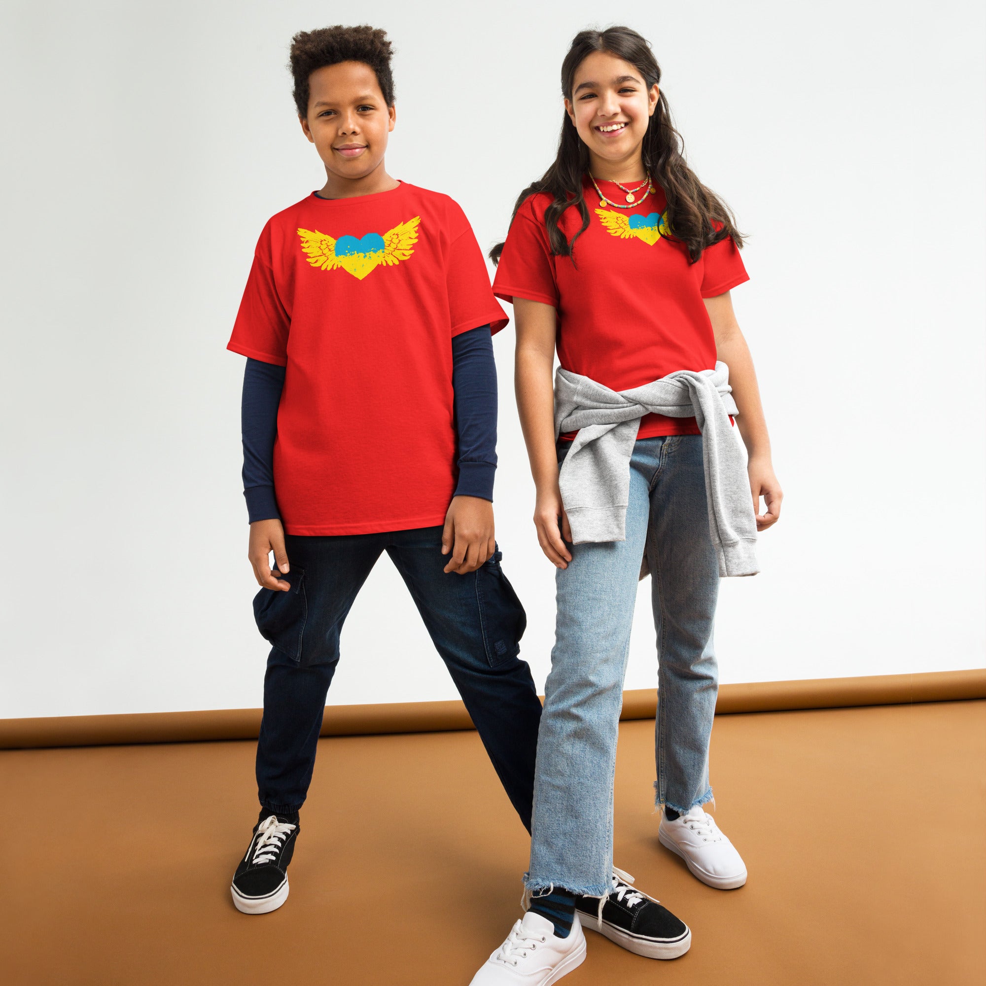 Two youths wearing red t-shirts with Ukrainian emblem, celebrating Ukrainian pride. Perfect for kids' active lifestyles.