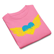 Folded pink t-shirt with a yellow and blue heart with wings graphic, symbolizing freedom and pride.